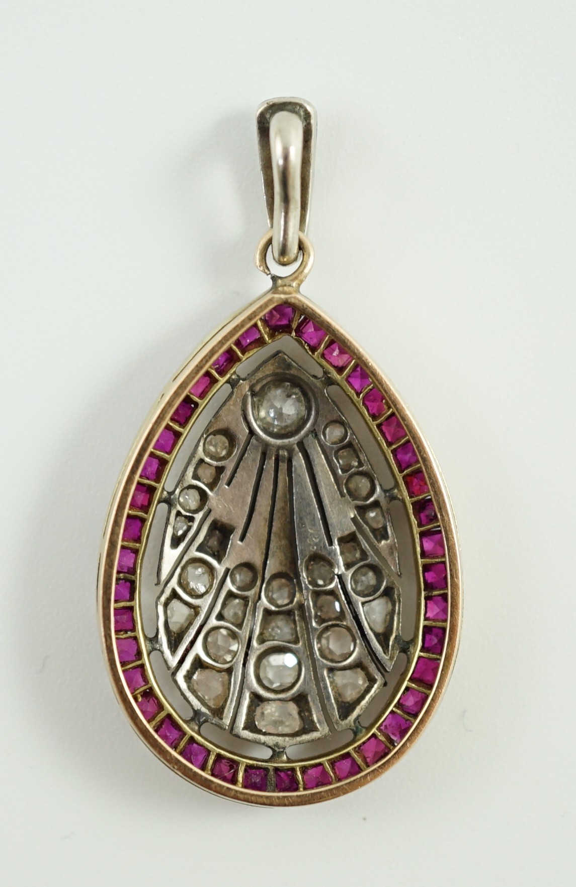 A 1920's pierced gold and platinum, millegrain set ruby and diamond oval pendant